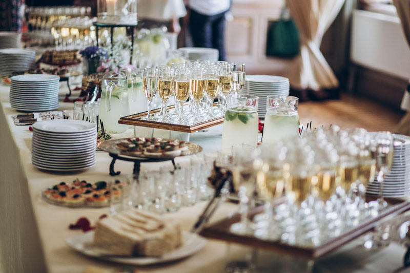 A catering station at a bridal shower is prepared and stocked with champagne, prepared food, and beverages prepared by the shower planner.
