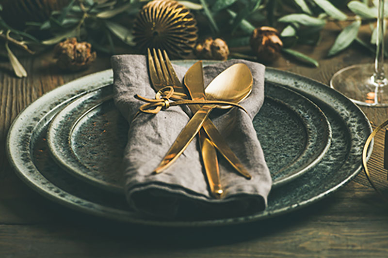 A set-piece prepared by event production company for a holiday party. Holiday color palettes are displayed with the dinner set piece on a wooden table.