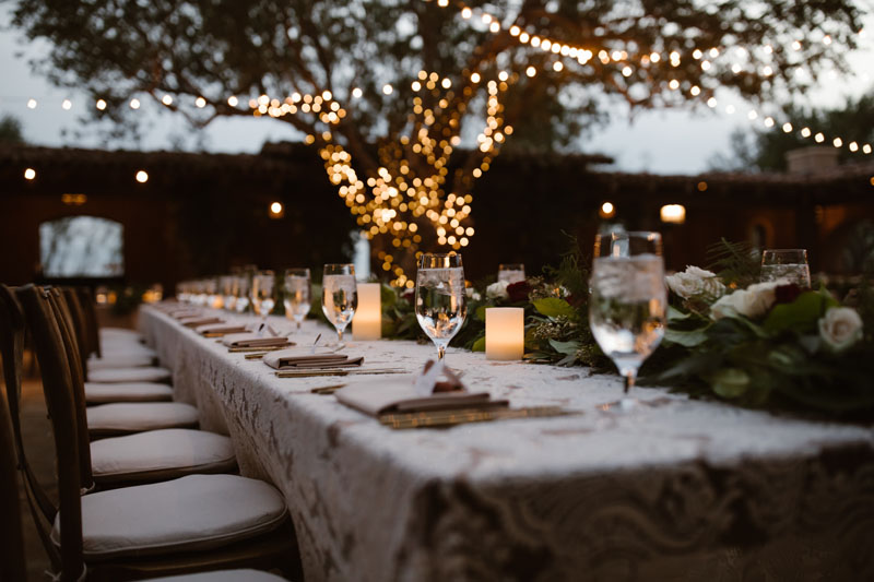 A rehearsal dinner planned and setup by an event planning agency awaits guests at a wedding venue.